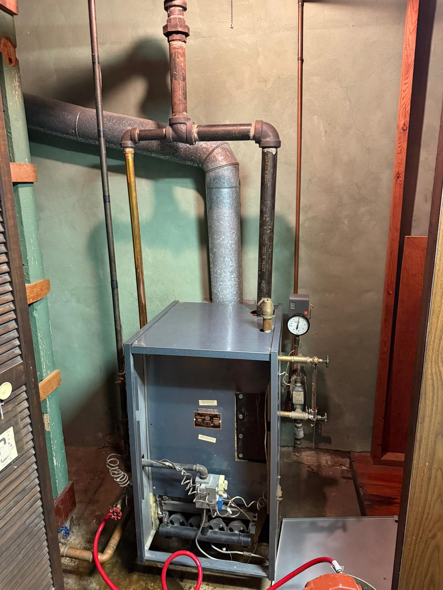 Residential boiler system with pipes and pressure gauge.
