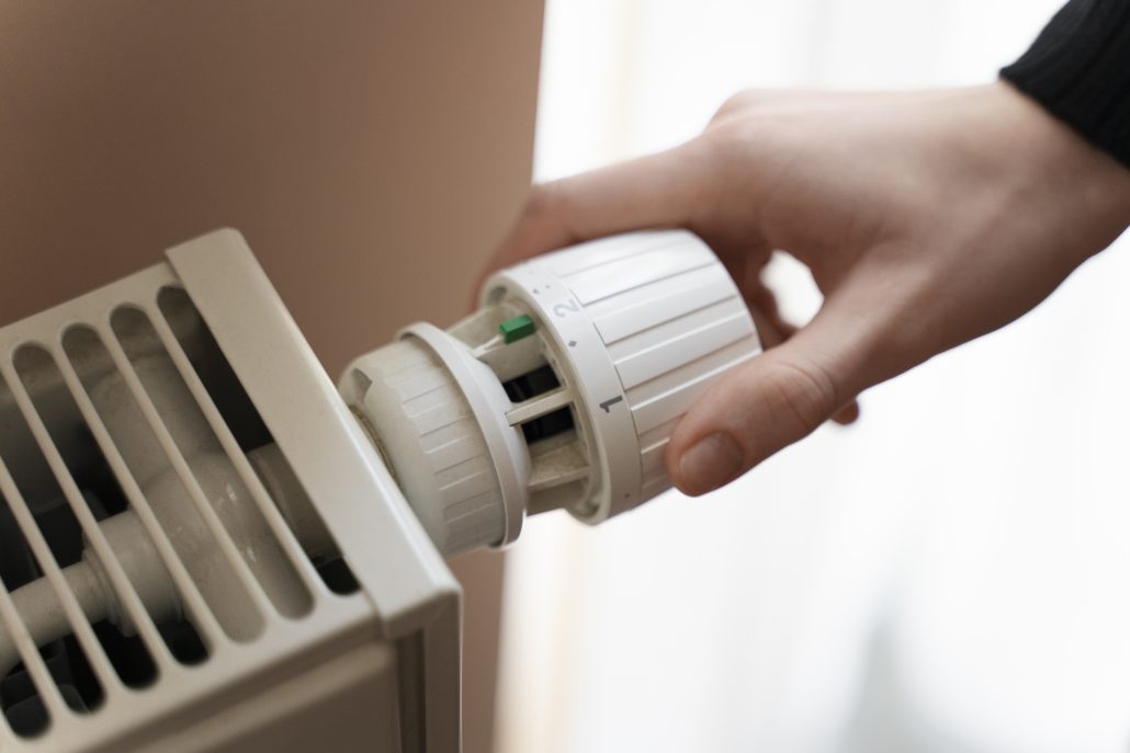 Close-up of a hand adjusting a radiator thermostat knob