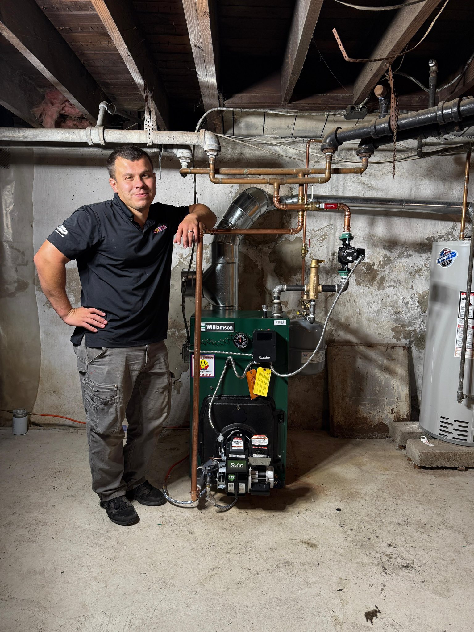 Oil-fired boiler with technician standing beside heating system in basement.