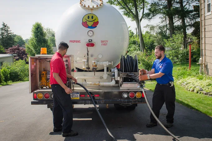 Propane delivery technicians from Boyle Energy filling a residential propane tank from a truck tanker.